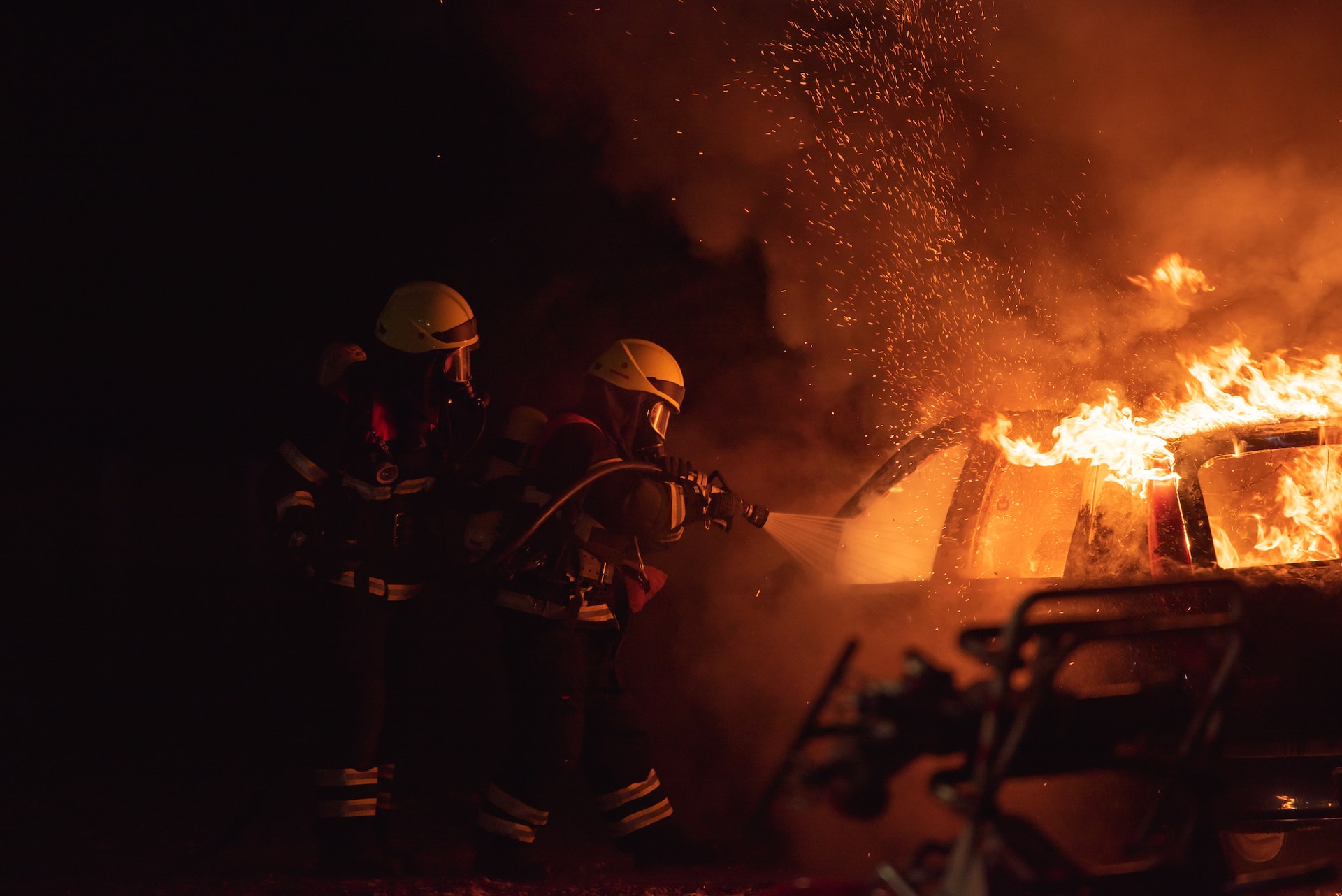 Two fully geared firefighters with a hose fighting a fire